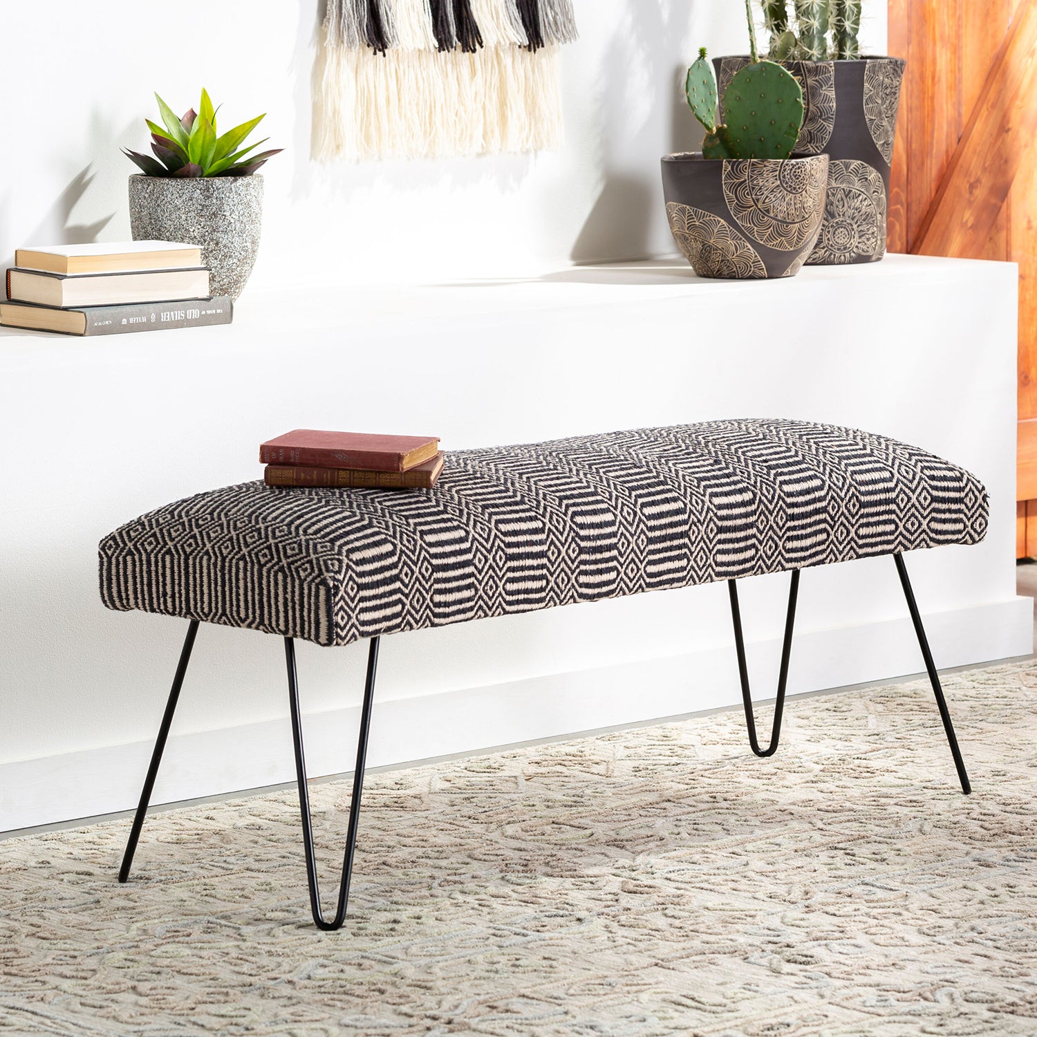 Patterned bench with black hairpin legs in a room setting with books and plants.