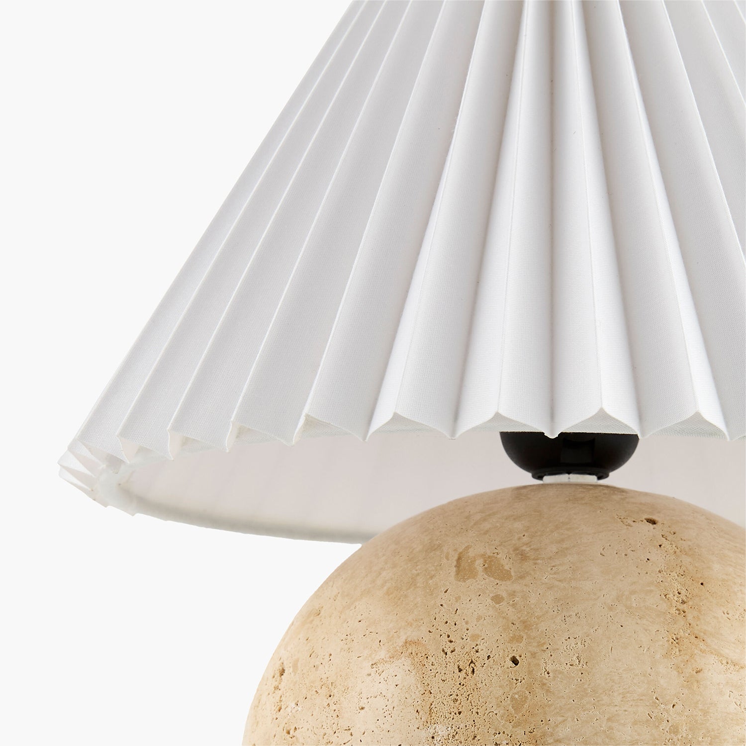 Close-up of a lamp with a pleated white shade and beige base.