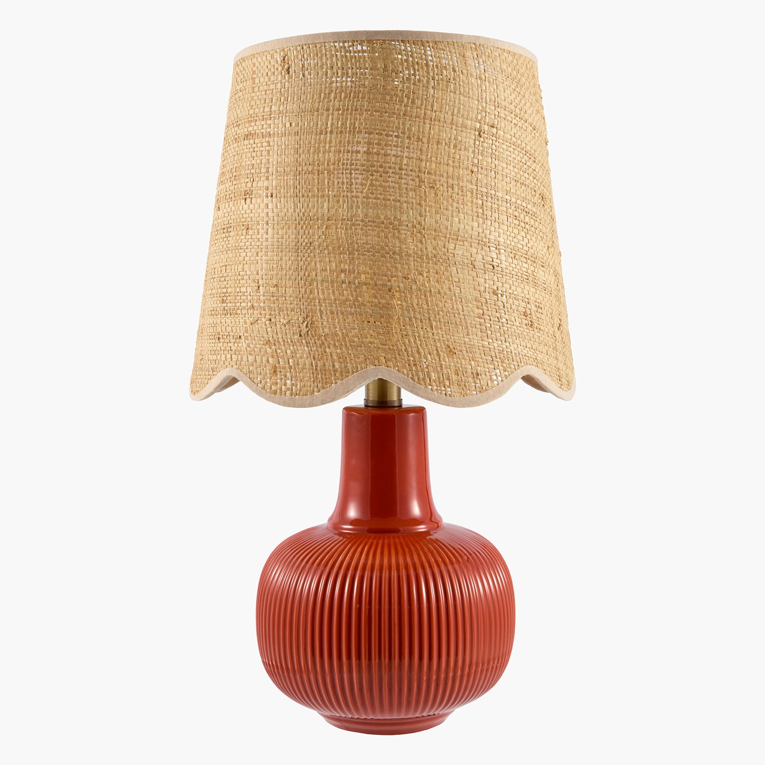 Table lamp with a textured beige shade and red ribbed base on a white background