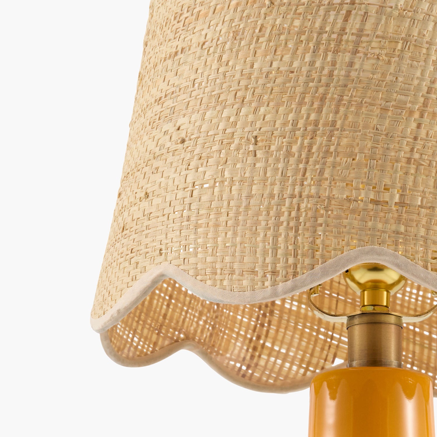 Close-up of a lamp with a wicker shade and gold base on a white background