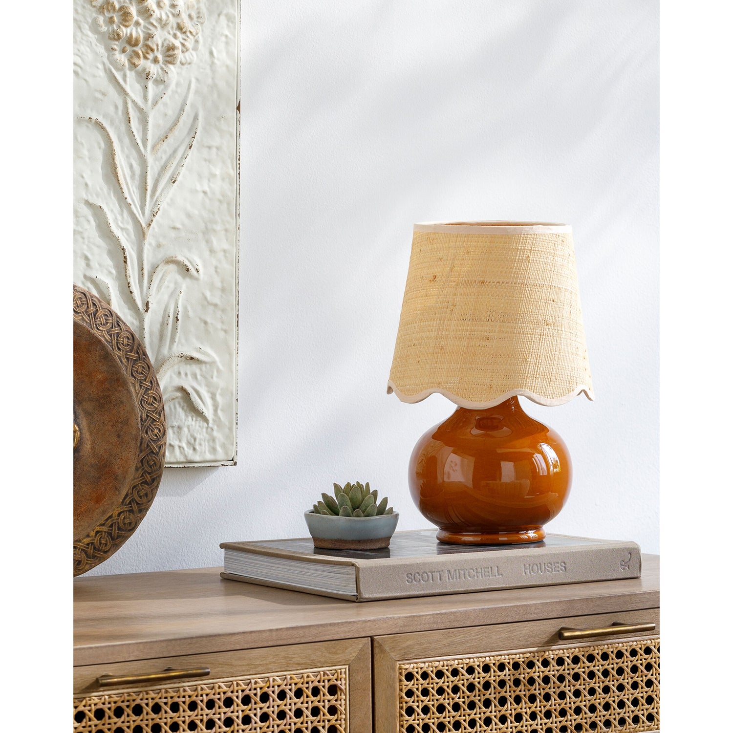 Brown lamp with beige shade on a wooden surface with decorative elements.